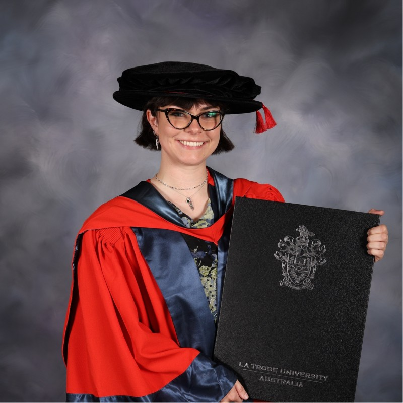 Dr. HLR in academic regalia holding a diploma from La Trobe University graduation ceremony